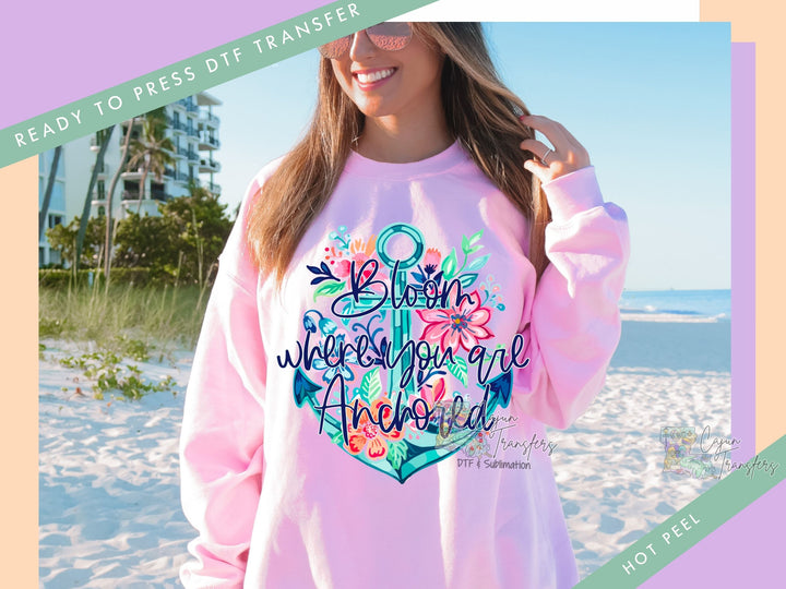 a woman standing on a beach wearing a pink sweatshirt