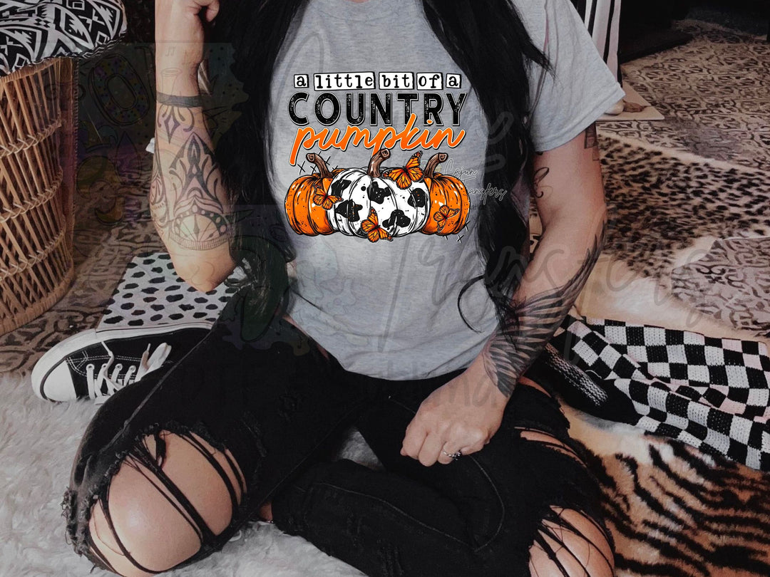 a woman sitting on the floor wearing a shirt that says country pumpkin
