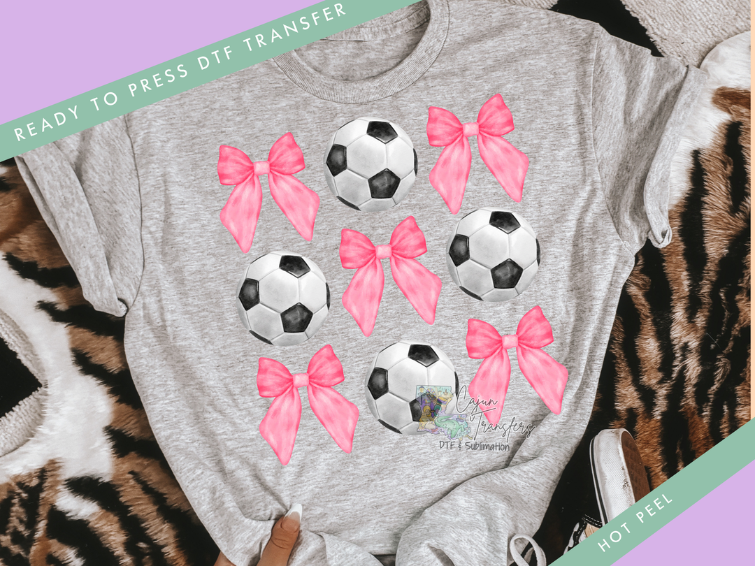 a gray shirt with pink bows and soccer balls on it