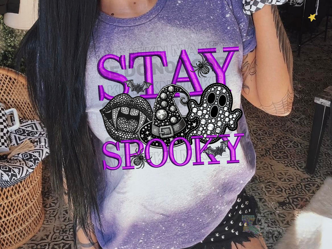 a woman with long black hair wearing a shirt that says stay spooky