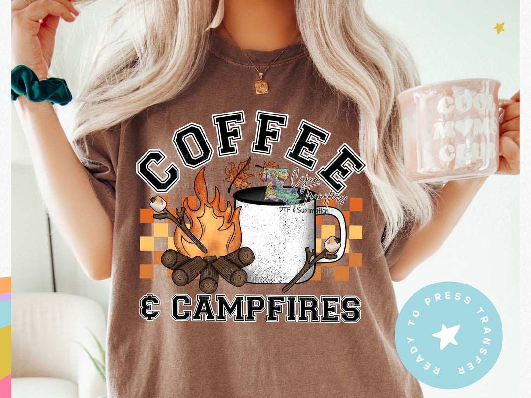 a woman holding a coffee mug with a campfire on it