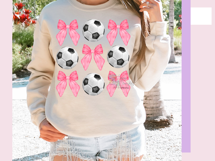 a woman wearing a sweatshirt with pink bows and soccer balls on it