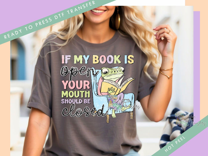 a woman wearing a t - shirt that says if my book is open your mouth