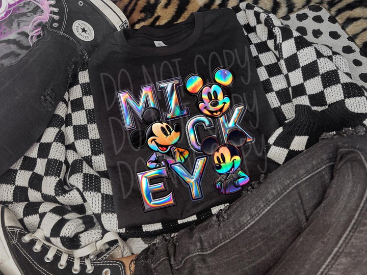 a mickey mouse shirt sitting on top of a pair of jeans