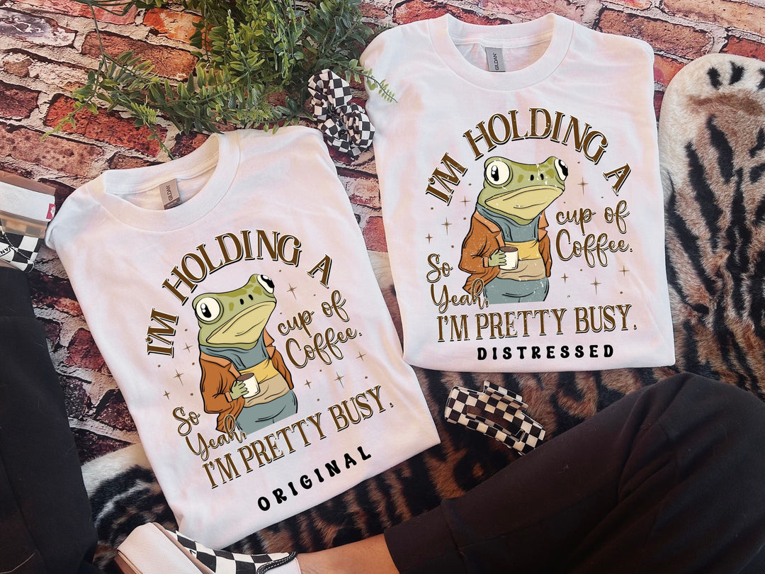 two t - shirts that say i'm holding a cup of coffee and i