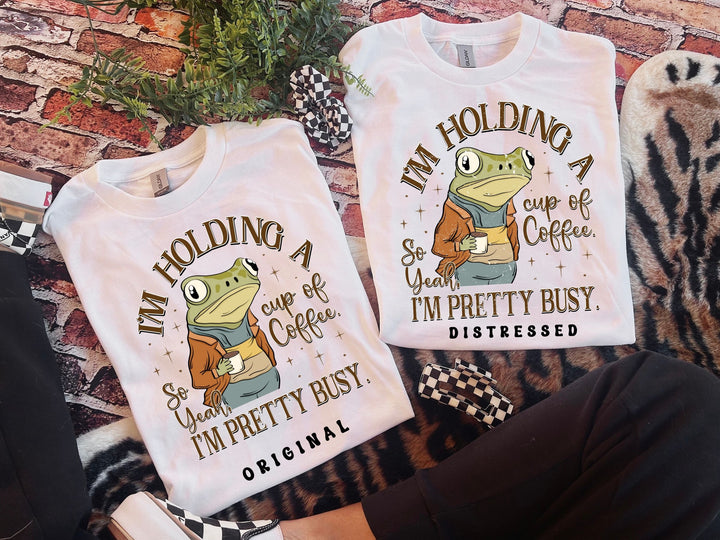 two t - shirts that say i'm holding a cup of coffee and i